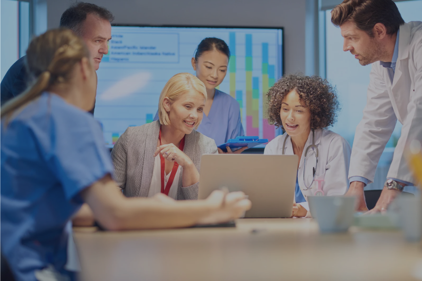 A multidisciplinary healthcare team reviews data and collaborates on strategy, reflecting innovation, cross-sector communication, and digital health leadership.